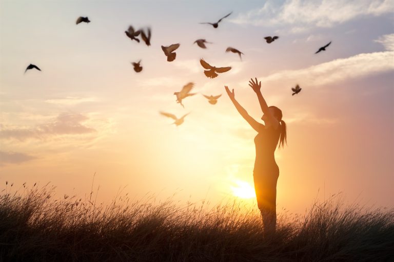 Woman investing in a peaceful moment, enjoying birds flying in the sunrise early in the morning