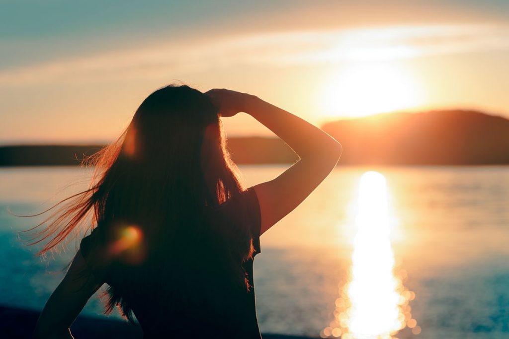 A lady looking out over the horizon of sea at a glimmer of hope for the New Year