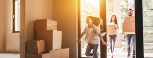 A young girl runs into her new home, her smiling parents following behind with boxes