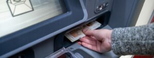Person at cashpoint withdrawing pension cash