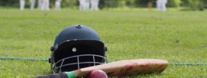 Cricket equipment with a match in background, a summer of sporting events