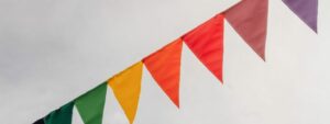 Red flag among colour pennants against clouds in the sky with sunshine