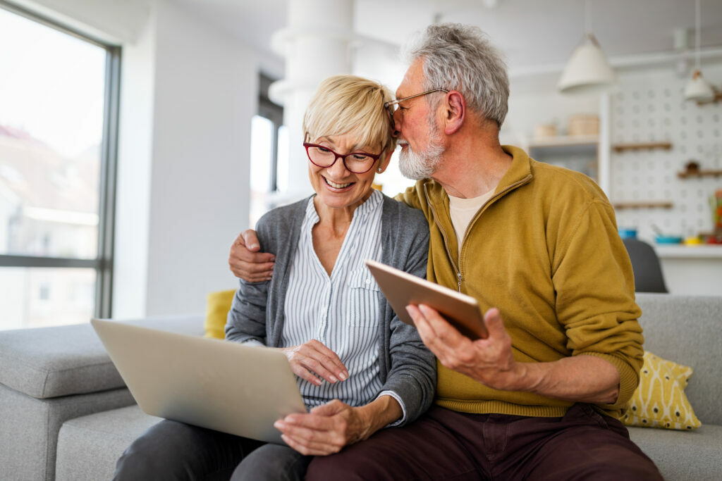 Retired couple at home on laptop, checking pension rates and IHT receipts