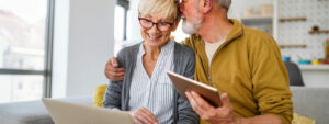 Retired couple at home on laptop, checking pension rates and IHT receipts
