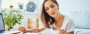 Young lady at kitchen table, using a calculator and trying to work out finances for mortgage