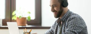 Man on laptop with headphones on, blocking out the noise