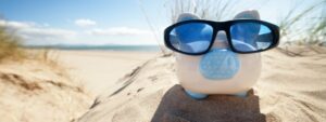 Piggy bank on beach wearing sunglasses, looking after your money to look after your life