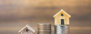 Mini wooden house concept and stack of coins, buyers priced out