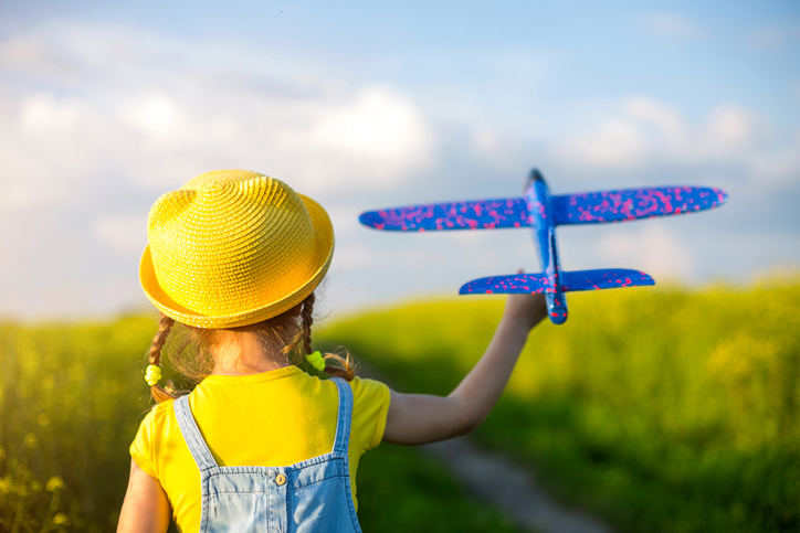 Little girl playing with toy aeroplane in the summer