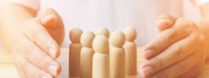 female hands covering wooden peg figures on a table to protect