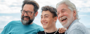 Portrait of three males laughing, grandfather, son and grandson stay together at the beach, smiling group of multi generation family enjoying good company expressing love and happiness