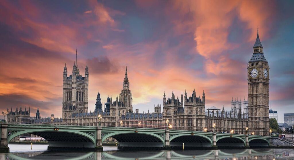 Stunning sunset over London's southern part with Westminster Abbey, Big Ben, Houses of Parliament, Westminster bridge and the Thames river flowing in the foreground.