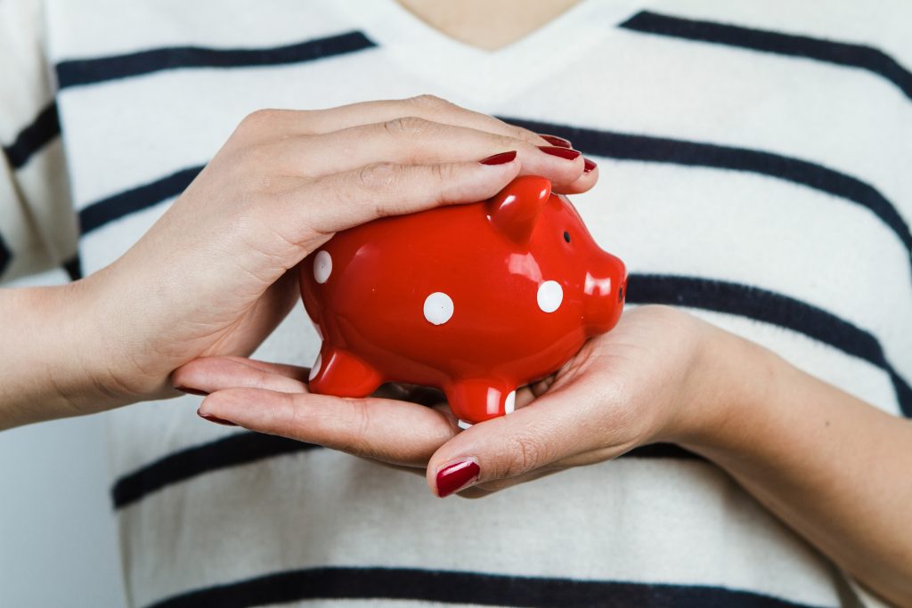 Lady cupping a piggy bank, using cash for savings