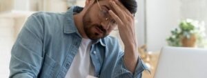 Upset, frustrated young man holding forehead, reading letter about long-term rental rates