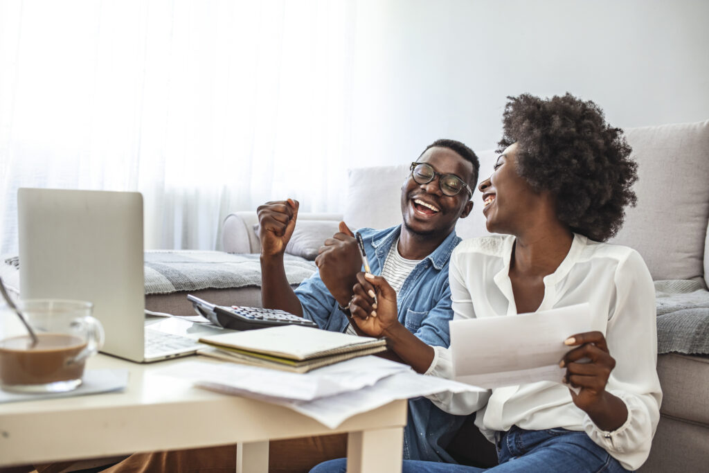 Happy couple looking at finances with laptop, calculator and documents
