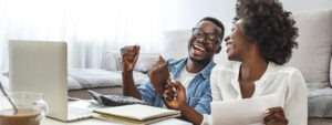 Happy couple looking at finances with laptop, calculator and documents