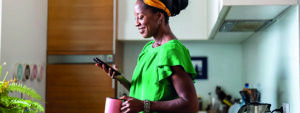 Woman standing in her kitchen looking at her property update on her phone