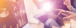 Businesspeople looking a graphs and stats on a computer, heeding lessons from the past on spreading risk