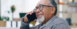 Senior man, happy and phone call on sofa with thinking, talking and contact in home living room. Elderly person, smartphone and smile for communication, conversation or relax on lounge couch in house